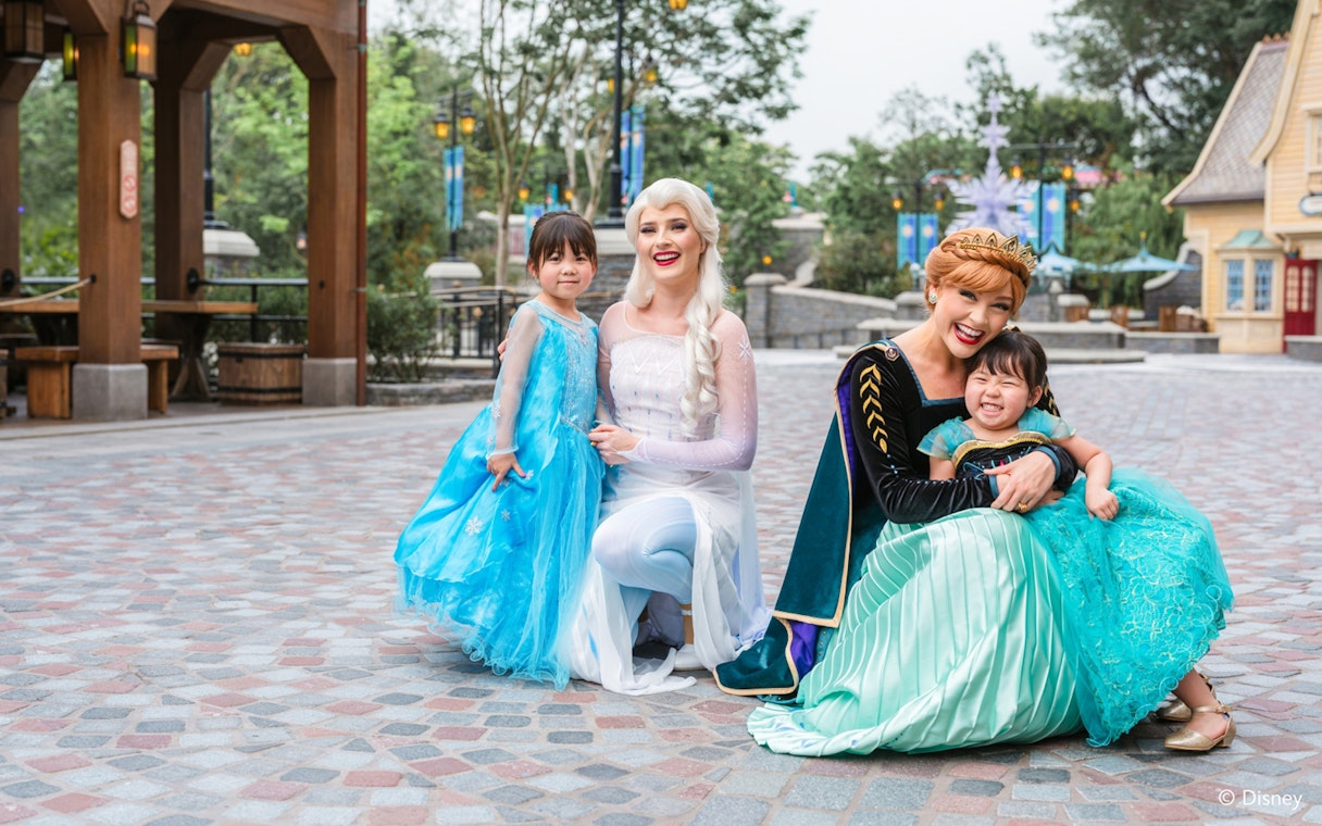 Elsa and Anna with children at Disneyland Hong Kong's Frozen Ever After attraction.