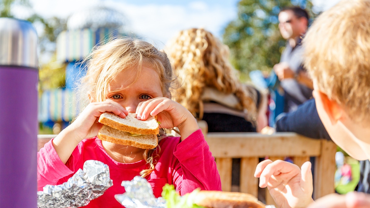 Child enjoying a sandwich during a picnic at Hampton Court.