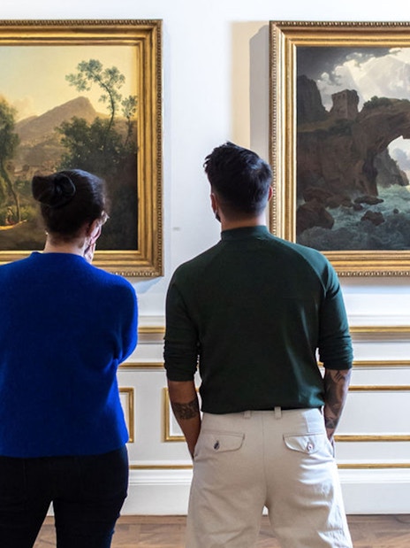 Visitors viewing landscape paintings in Belvedere Palace, Vienna.