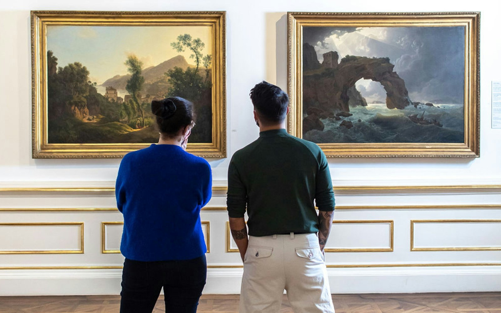 Visitors viewing landscape paintings in Belvedere Palace, Vienna.