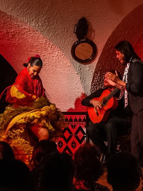Flamenco dancer performing at Tablao Cordobes with guitarist and clapping audience.