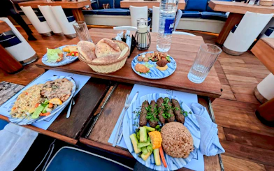 Nile Dahabiya dinner cruise meal with bread, rice, kebabs, and vegetables on a wooden table.