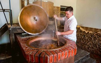 Brewer stirring a large vat at Dětenice Brewery during Prague medieval dinner show tour.