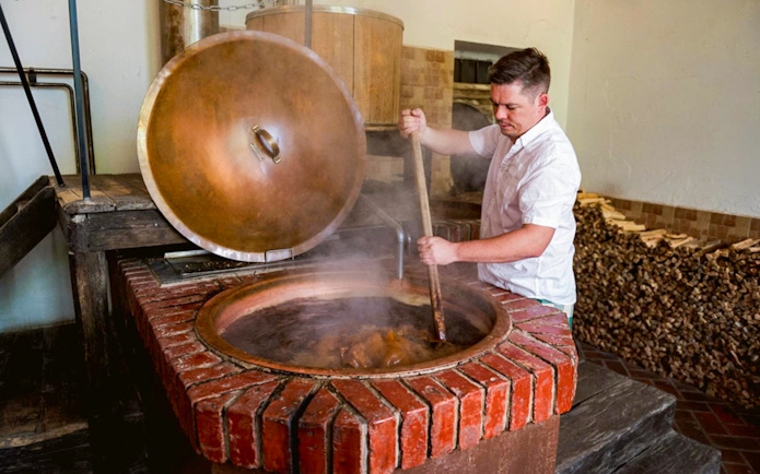 Brewer stirring a large vat at Dětenice Brewery during Prague medieval dinner show tour.