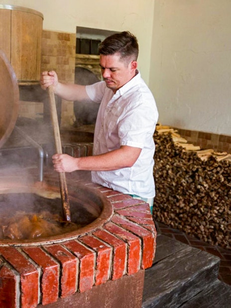 Brewer stirring a large vat at Dětenice Brewery during Prague medieval dinner show tour.
