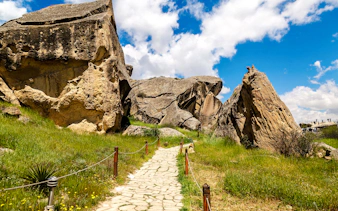 Gobustan rock formations and path under blue sky, Baku tour.