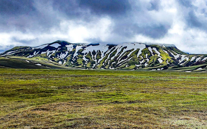 Landmannalaugar Highlands with snow-capped mountains and green plains, Iceland.