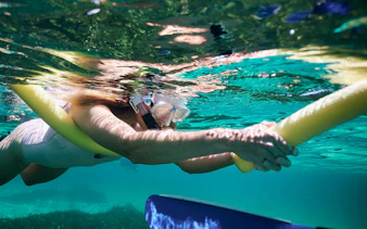 Snorkeling woman holding float in clear waters at Rottnest Island.