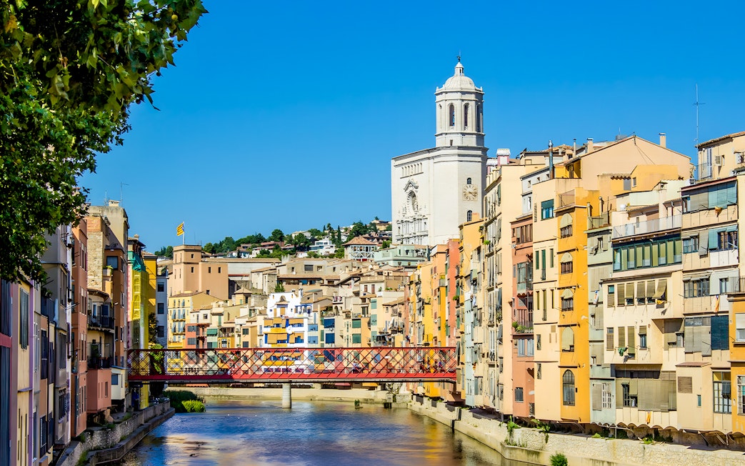 Colorful houses along the Onyar River with Girona Cathedral in the background, Girona, Spain.