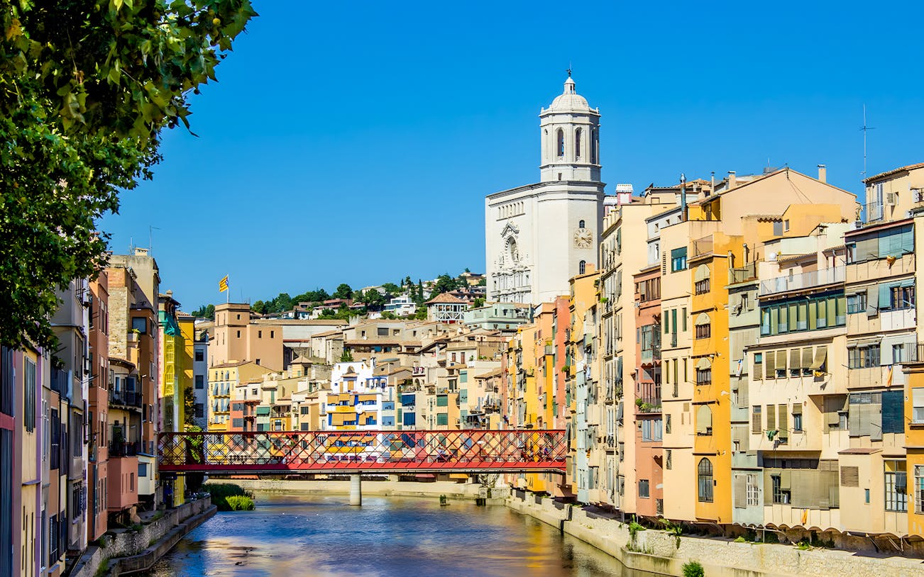 Colorful houses along the Onyar River with Girona Cathedral in the background, Girona, Spain.