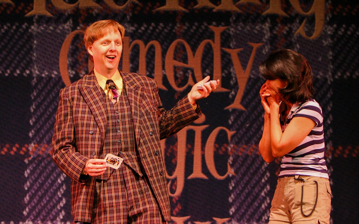 Magician performing card trick with audience member at The Mac King Comedy Magic Show, Vegas.