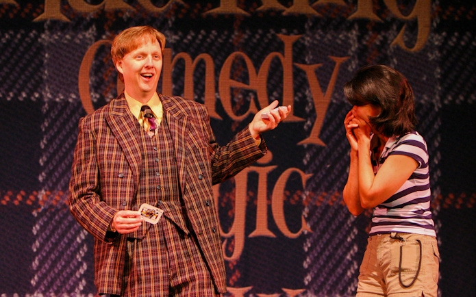 Magician performing card trick with audience member at The Mac King Comedy Magic Show, Vegas.