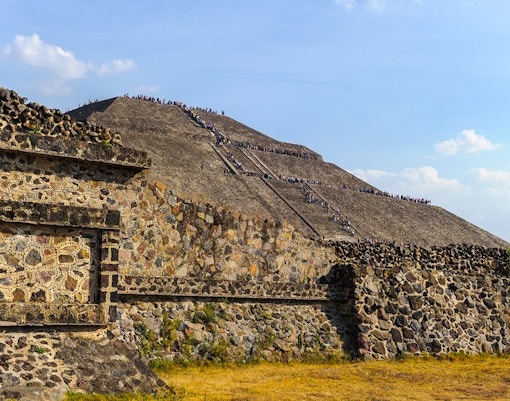 Pyramid of the Sun in Teotihuacan, Mexico, with visitors climbing the ancient stone steps.