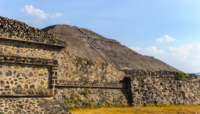 Pyramid of the Sun in Teotihuacan, Mexico, with visitors climbing the ancient stone steps.