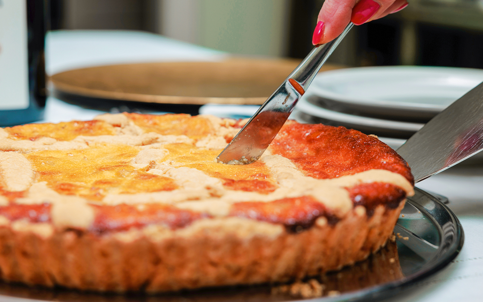 Slicing a homemade Neapolitan pastiera, showcasing its rich texture and traditional Italian dessert appeal.