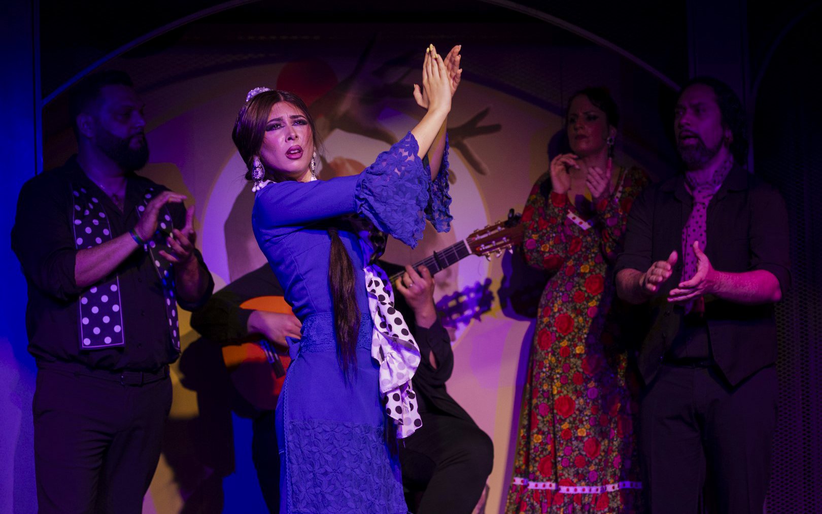 Flamenco dancer performing at El Duende by Tablao Cordobes with musicians clapping.