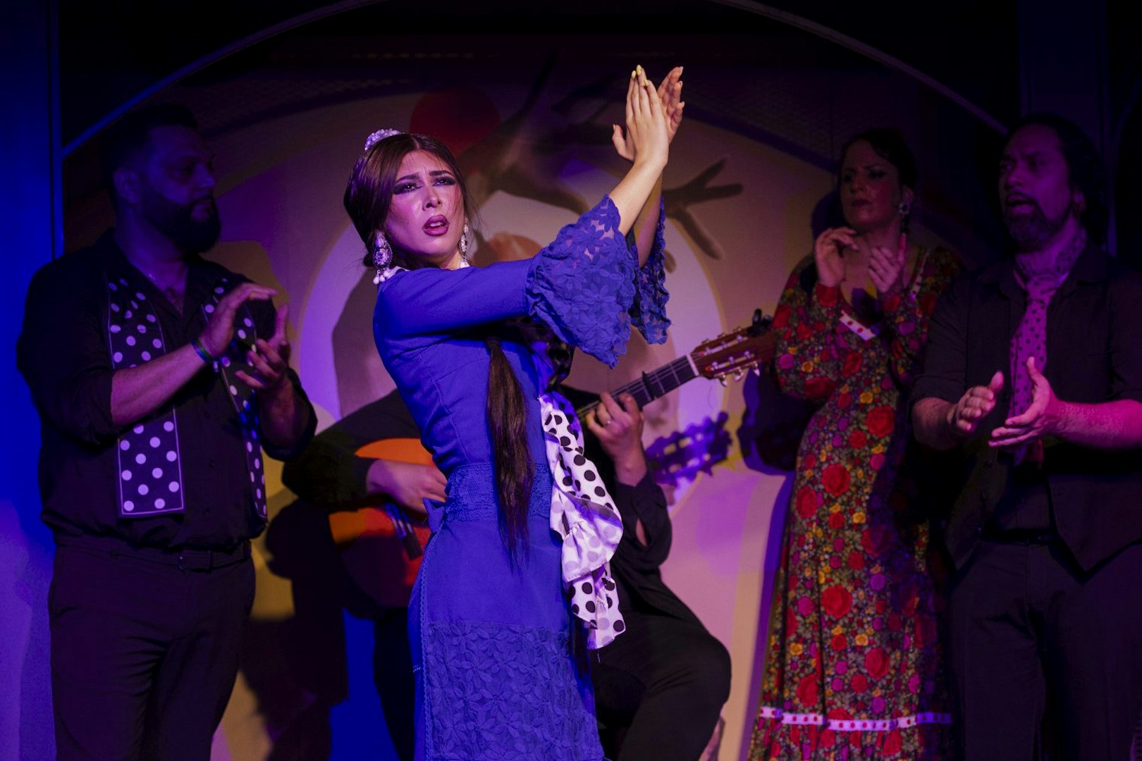Flamenco dancer performing at El Duende by Tablao Cordobes with musicians clapping.