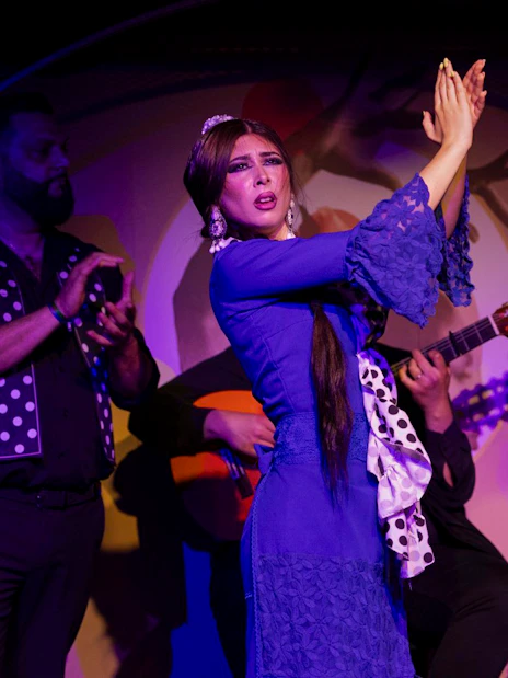Flamenco dancer performing at El Duende by Tablao Cordobes with musicians clapping.