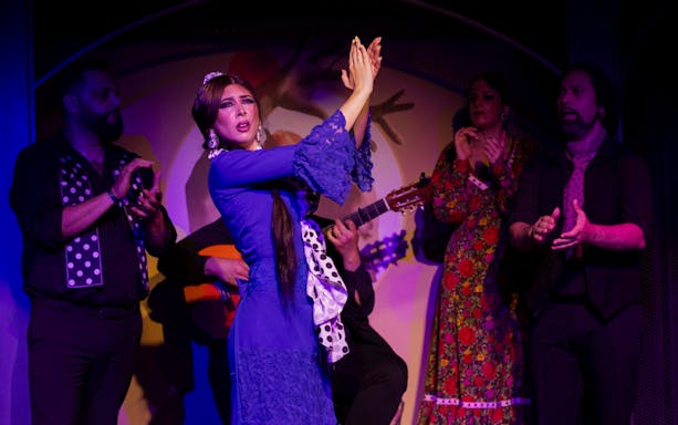 Flamenco dancer performing at El Duende by Tablao Cordobes with musicians clapping.