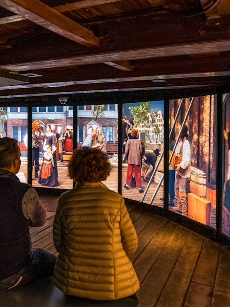 Visitors viewing historical exhibit at The Maritime Museum, Amsterdam.
