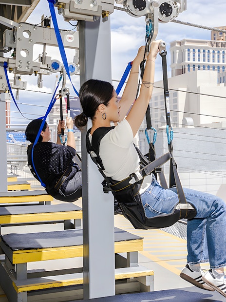 People ziplining at Fly LINQ Zipline with Las Vegas skyline in the background.