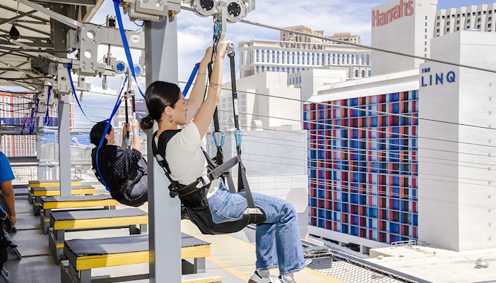 People ziplining at Fly LINQ Zipline with Las Vegas skyline in the background.