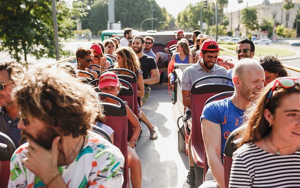 Group of tourists enjoying Derry Hop-On-Hop-Off bus tour on a sunny day.