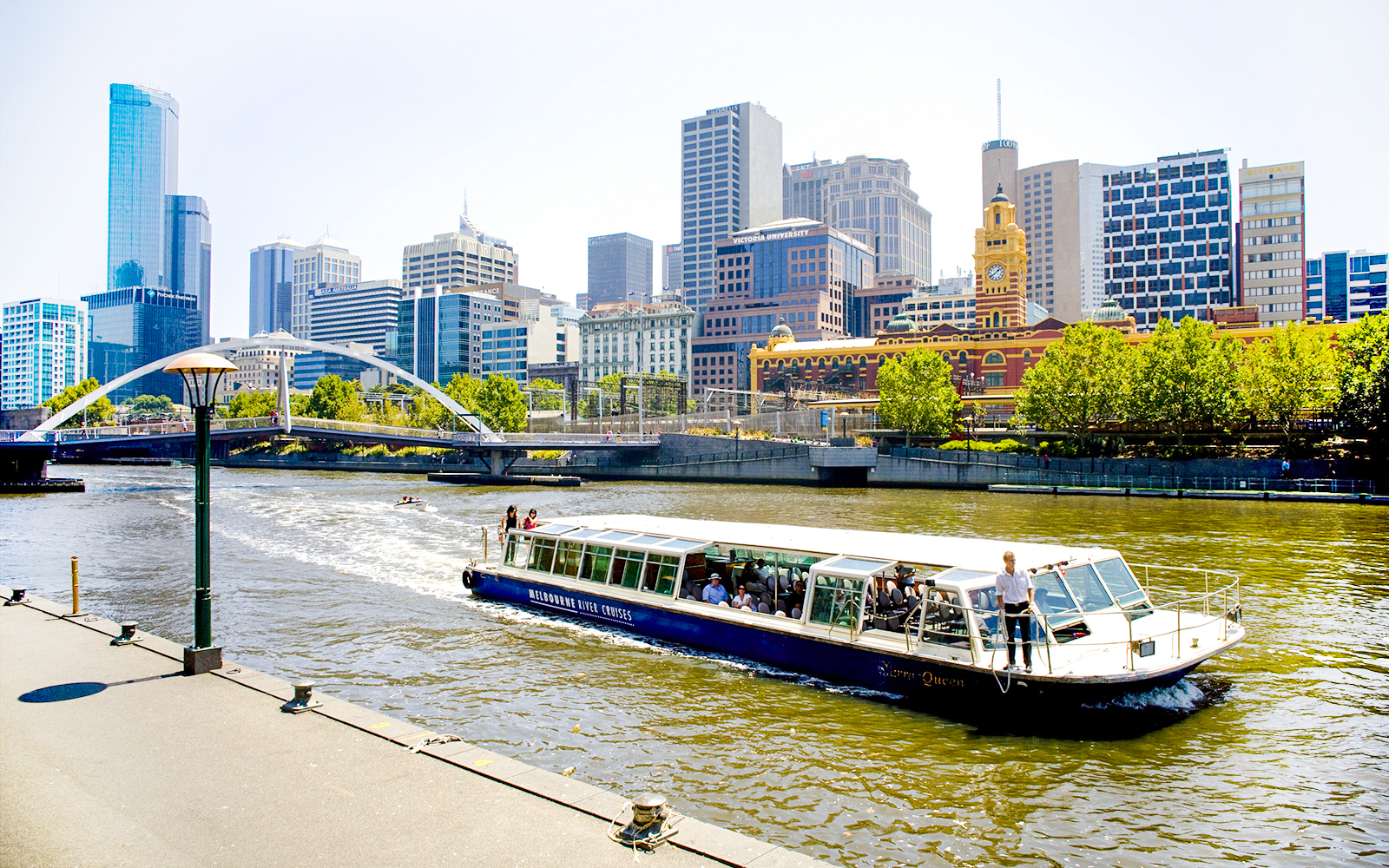 Melbourne River Cruises boat on Yarra River with city skyline in background.