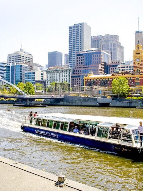 Melbourne River Cruises boat on Yarra River with city skyline in background.