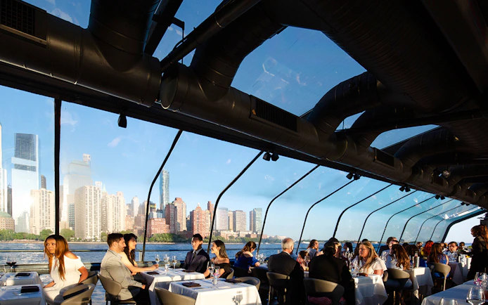 Guests dining on a New Jersey Signature Cruise with city skyline views.