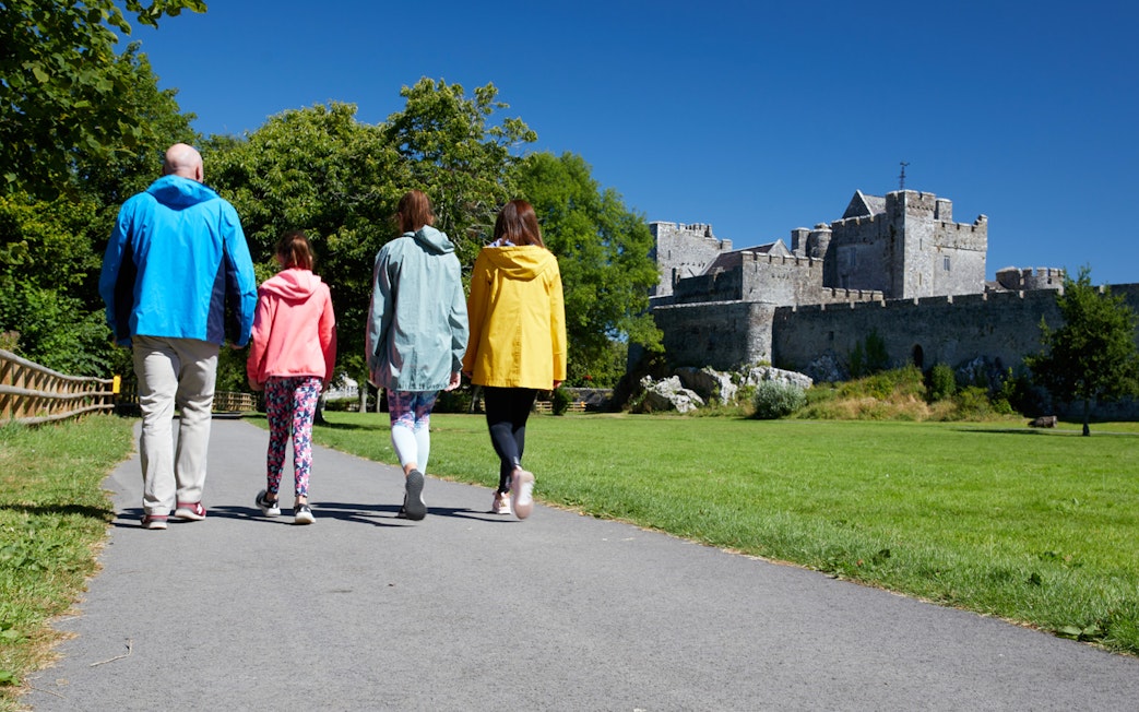 Group walking towards historic castle on a sunny day.