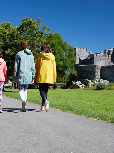 Group walking towards historic castle on a sunny day.