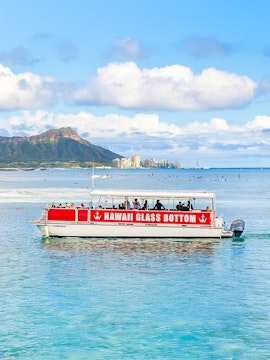 Glass-bottom boat tour off Waikiki coast with Diamond Head in background, Hawaii.