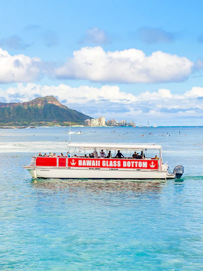 Glass-bottom boat tour off Waikiki coast with Diamond Head in background, Hawaii.