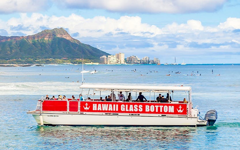 Glass-bottom boat tour off Waikiki coast with Diamond Head in background, Hawaii.