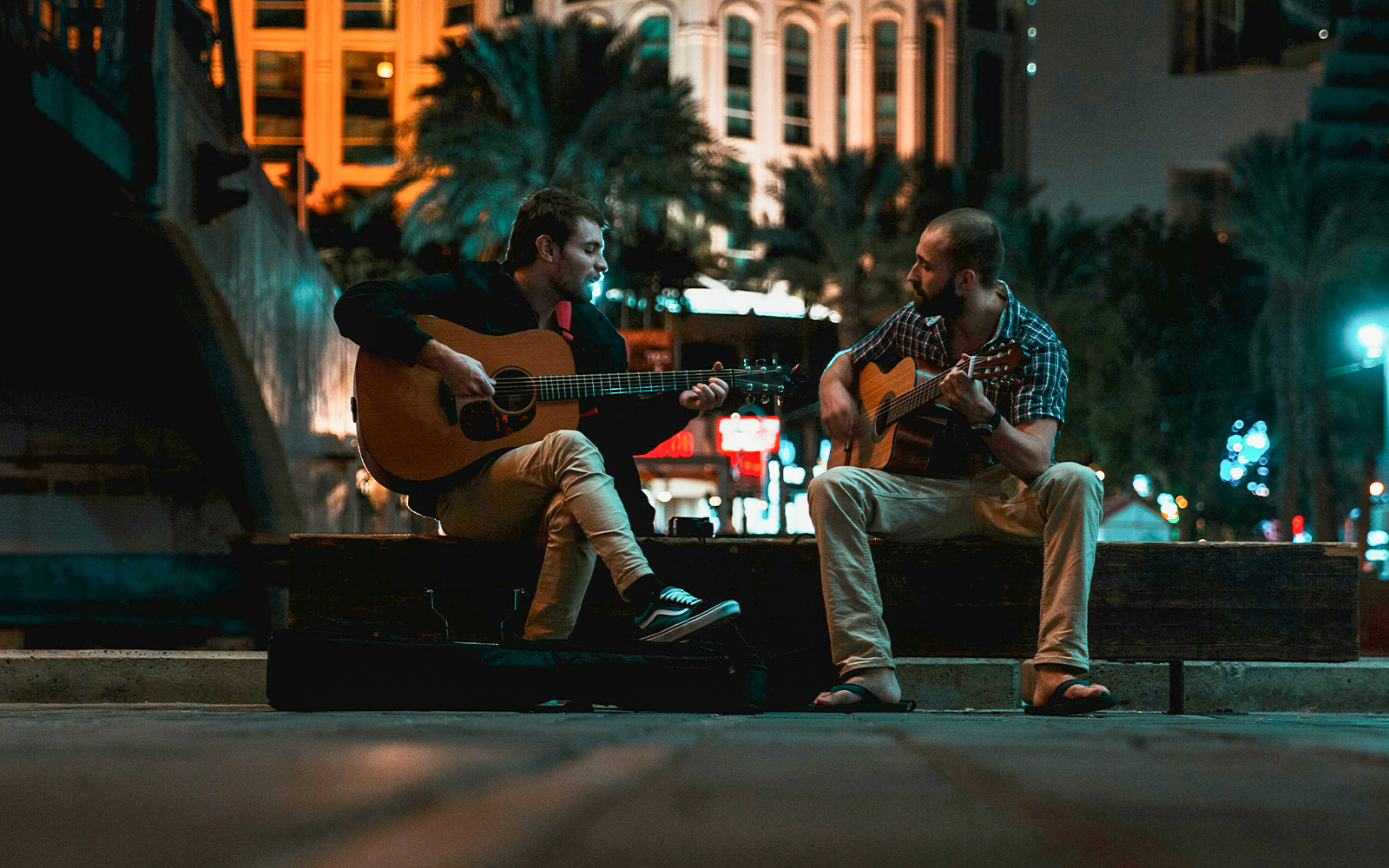 Two guitar players performing at a park in Barcelona at night.