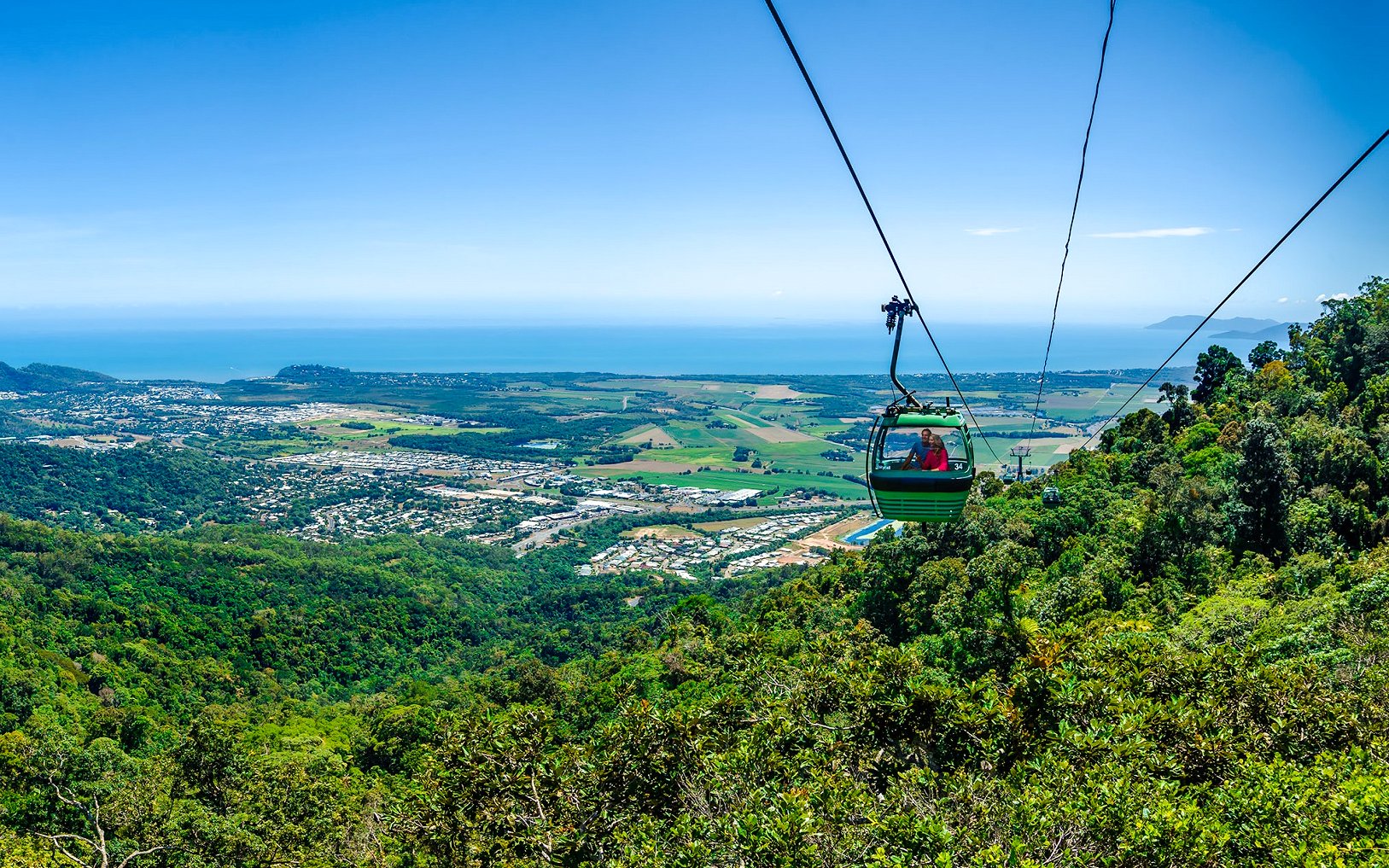 Cable car over lush rainforest with ocean view on Scenic Train and Skyrail Kuranda Tour.