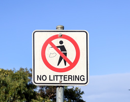 No littering sign against a clear blue sky.