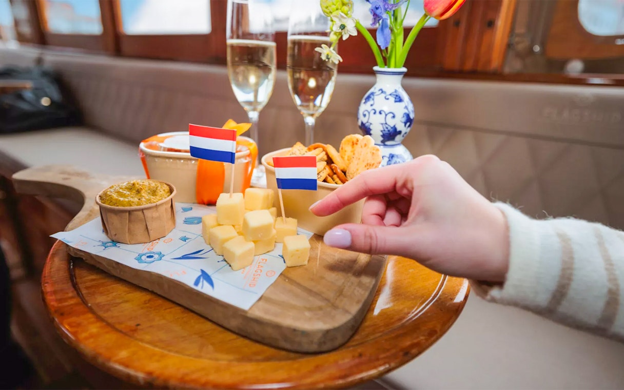 Cheese cubes with Dutch flags and wine on Amsterdam luxury cruise table.