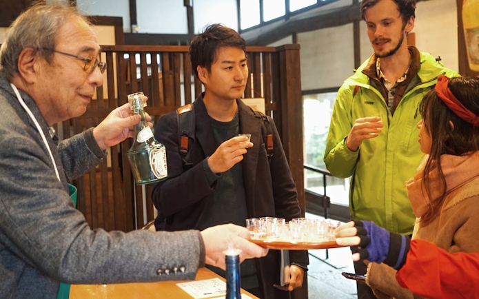 Visitors tasting sake at a Kyoto brewery during a guided walking tour.