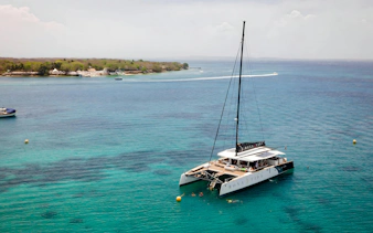Catamaran anchored near Rosario Islands with people swimming in clear blue water.