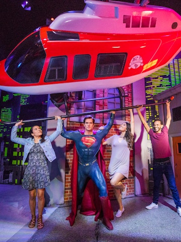Superman figure lifting helicopter with visitors at Madame Tussauds Orlando.