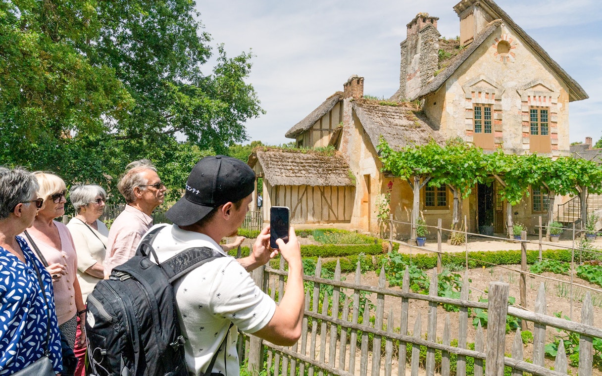 Tourists viewing a rustic cottage in the Domain of Marie-Antoinette, Versailles.