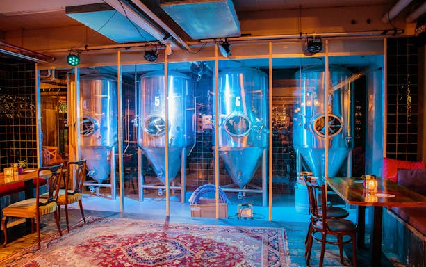 Brewery interior with fermentation tanks and seating area, part of craft beer tour.