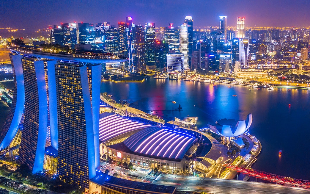 Singapore skyline at night viewed from the Singapore Flyer, featuring Marina Bay Sands and city lights.