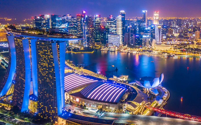 Singapore skyline at night viewed from the Singapore Flyer, featuring Marina Bay Sands and city lights.