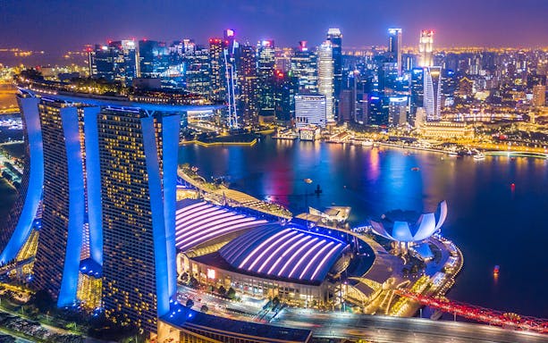 Singapore skyline at night viewed from the Singapore Flyer, featuring Marina Bay Sands and city lights.