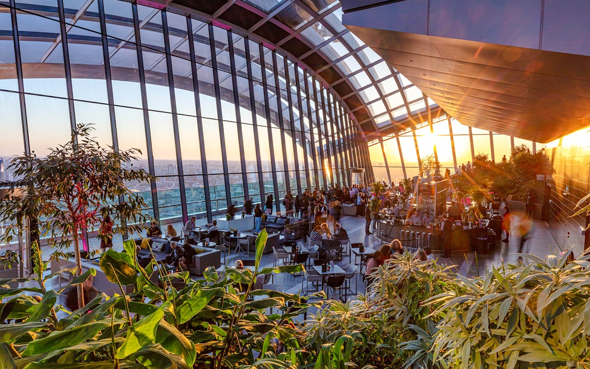 Sky Garden London evening view with people dining and cityscape backdrop.