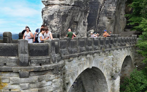 Visitors exploring Bastei Bridge during guided tour, Saxon Switzerland, Germany.