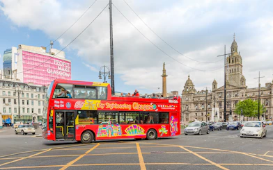 Open-top sightseeing bus in George Square, Glasgow, with City Chambers in the background.